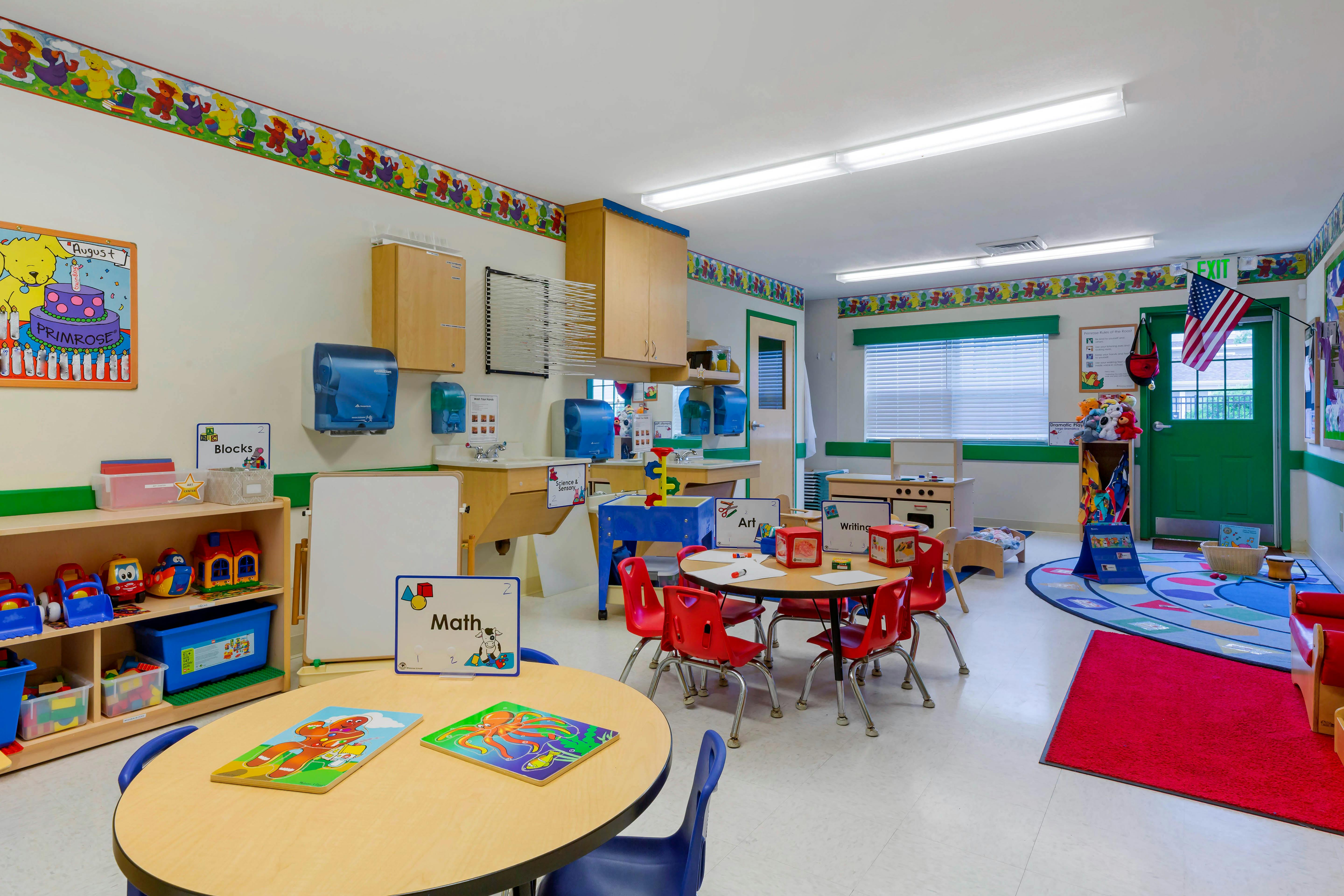 Classroom with child-sized tables and chairs, play kitchen, and educational signs