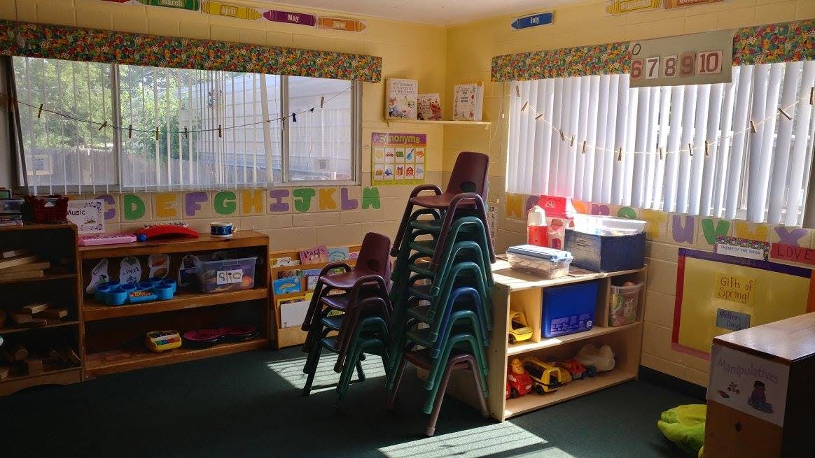 Classroom with stacked chairs and shelves