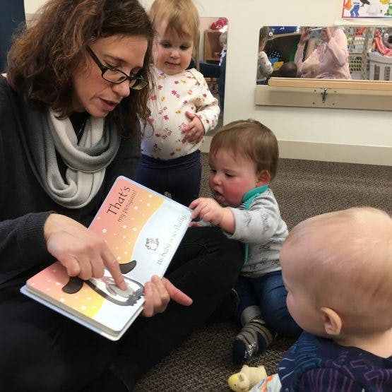 Person reading a book to three children
