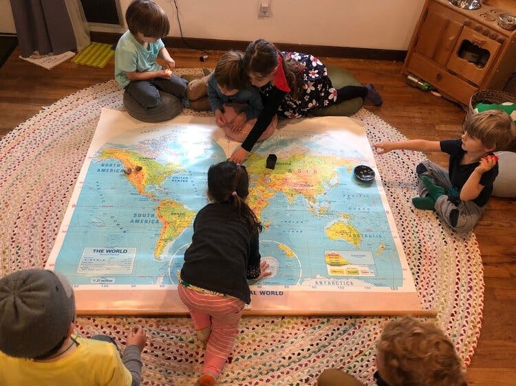 Children gathered around a large world map on the floor