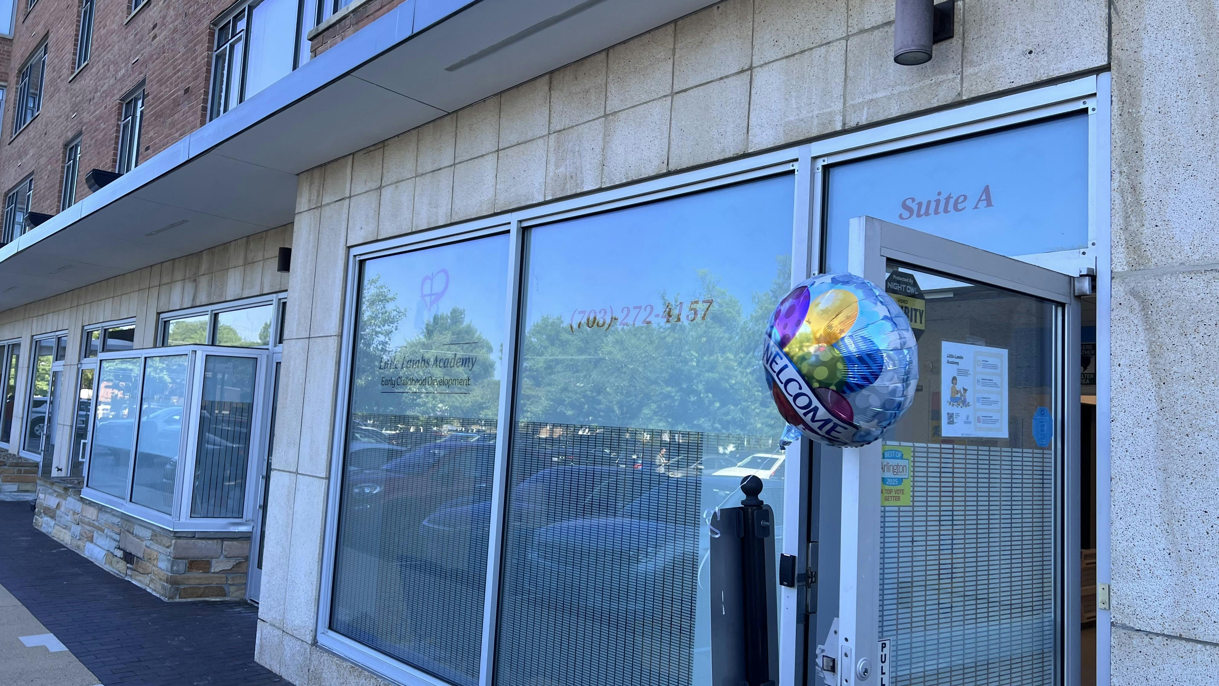 Storefront with a colorful 'WELCOME' balloon tied to the door handle
