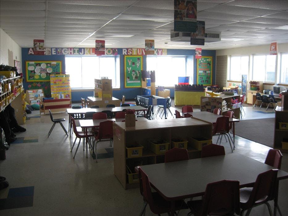 Empty classroom with small tables and chairs, ABCs on the wall
