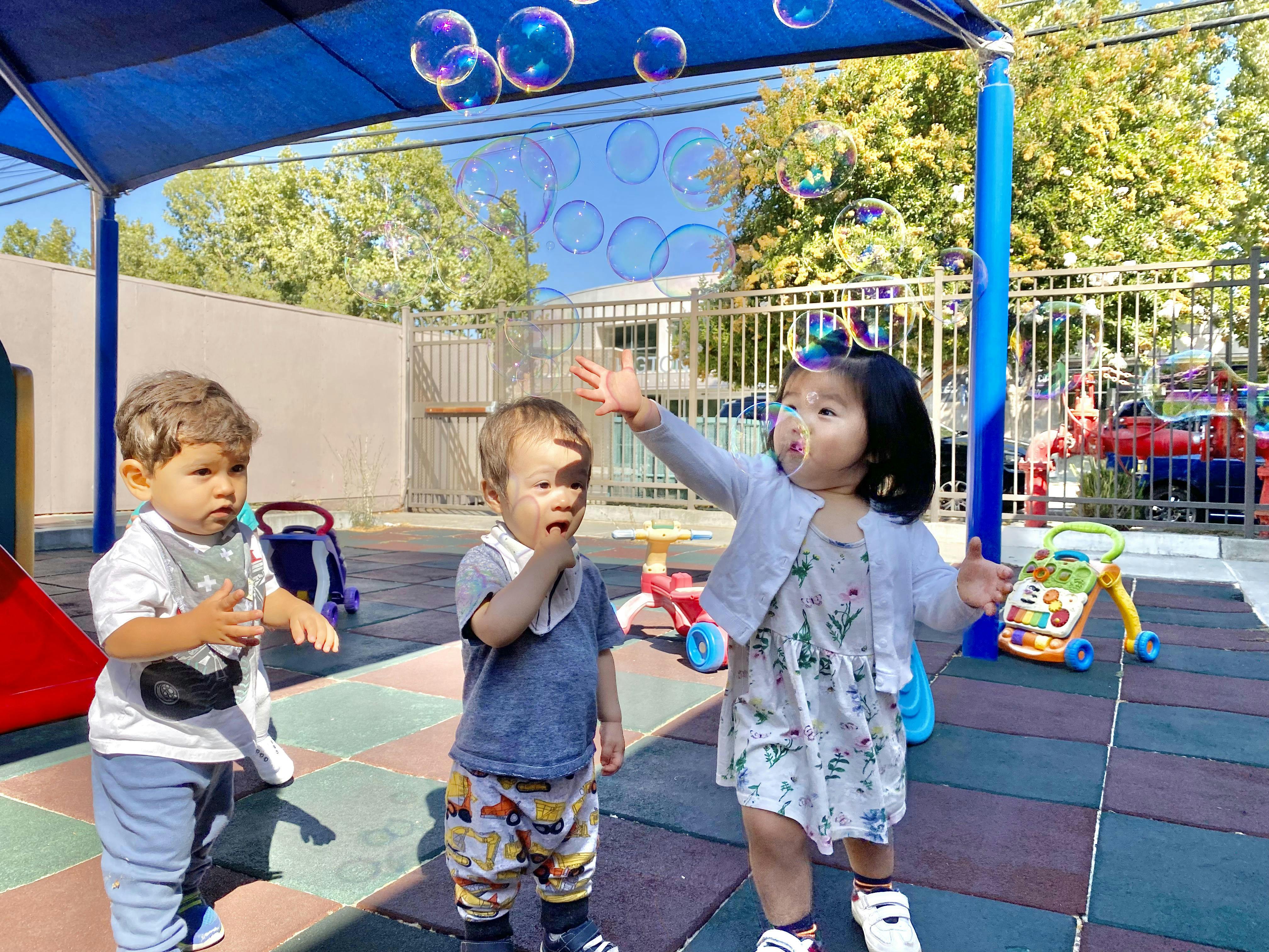 Three children playing with bubbles outdoors