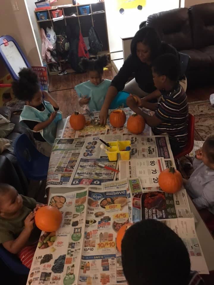 Adult and children carving pumpkins at a table