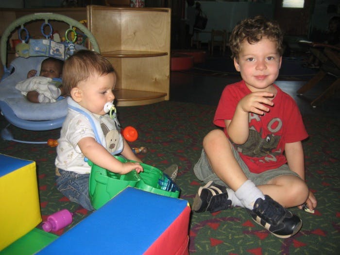 Two children sitting on a carpeted floor with toys