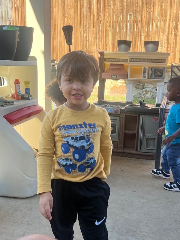 Child in a yellow shirt with a monster truck graphic