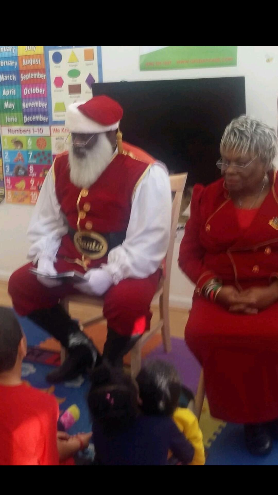 Person dressed as Santa Claus and another person sitting with children