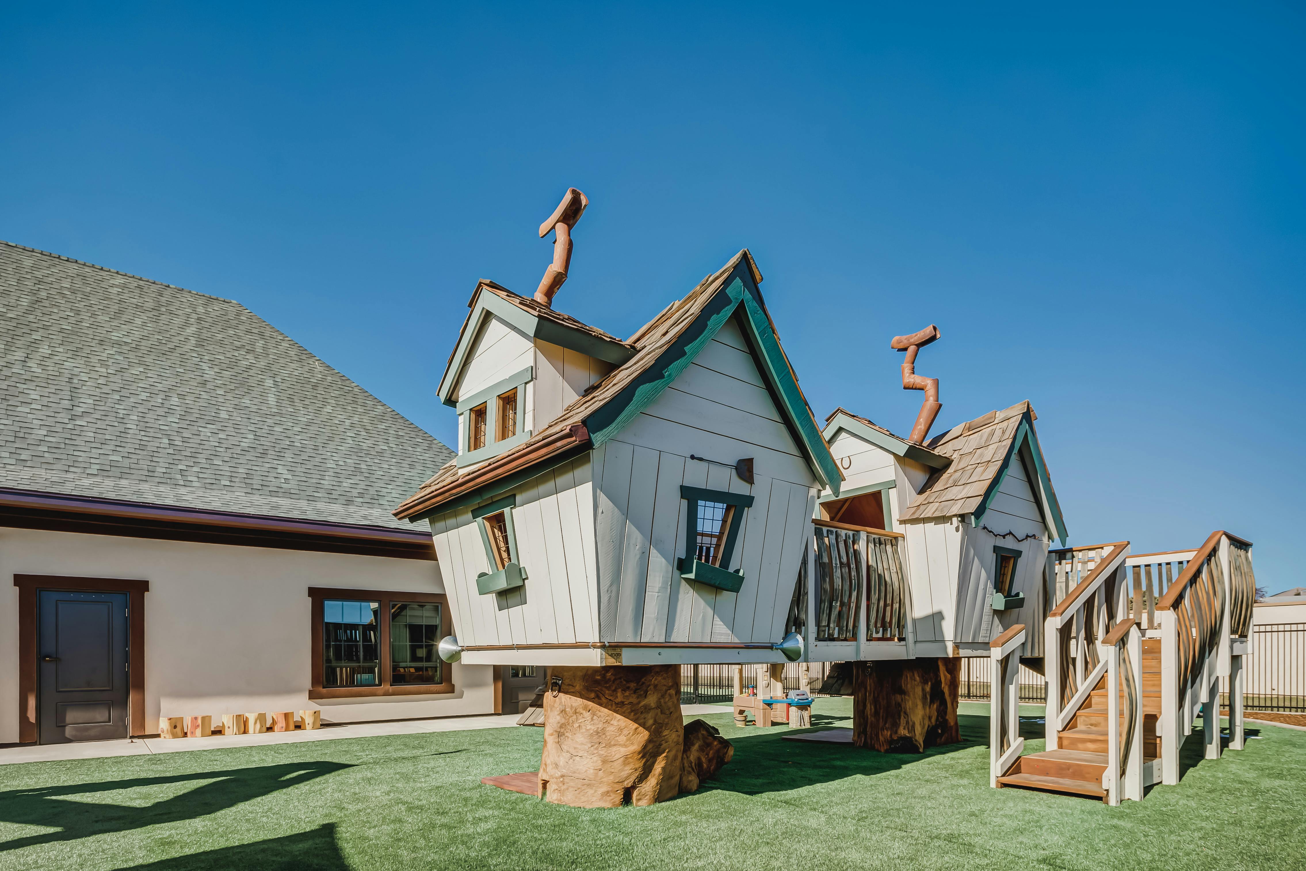 Playground with treehouse-like structures and stairs on artificial turf