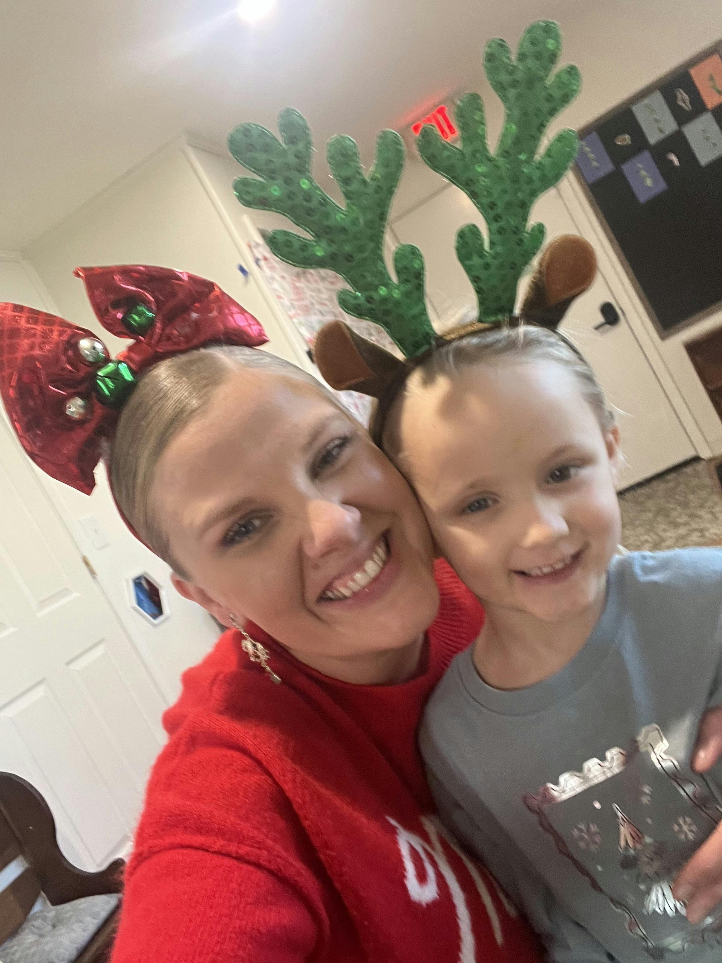 Person in red bow headband and child in reindeer antler headband