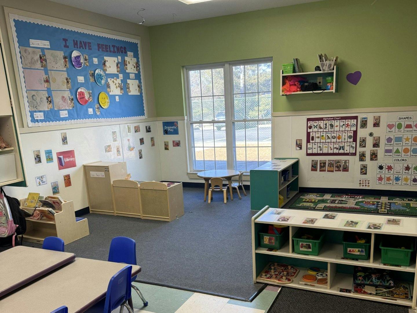 Empty classroom with student artwork, alphabet charts, and play areas