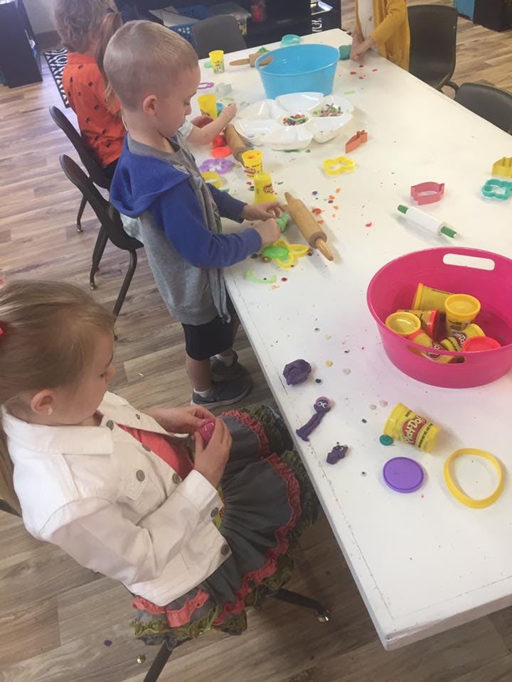 Child playing with playdough and rolling pin at a table