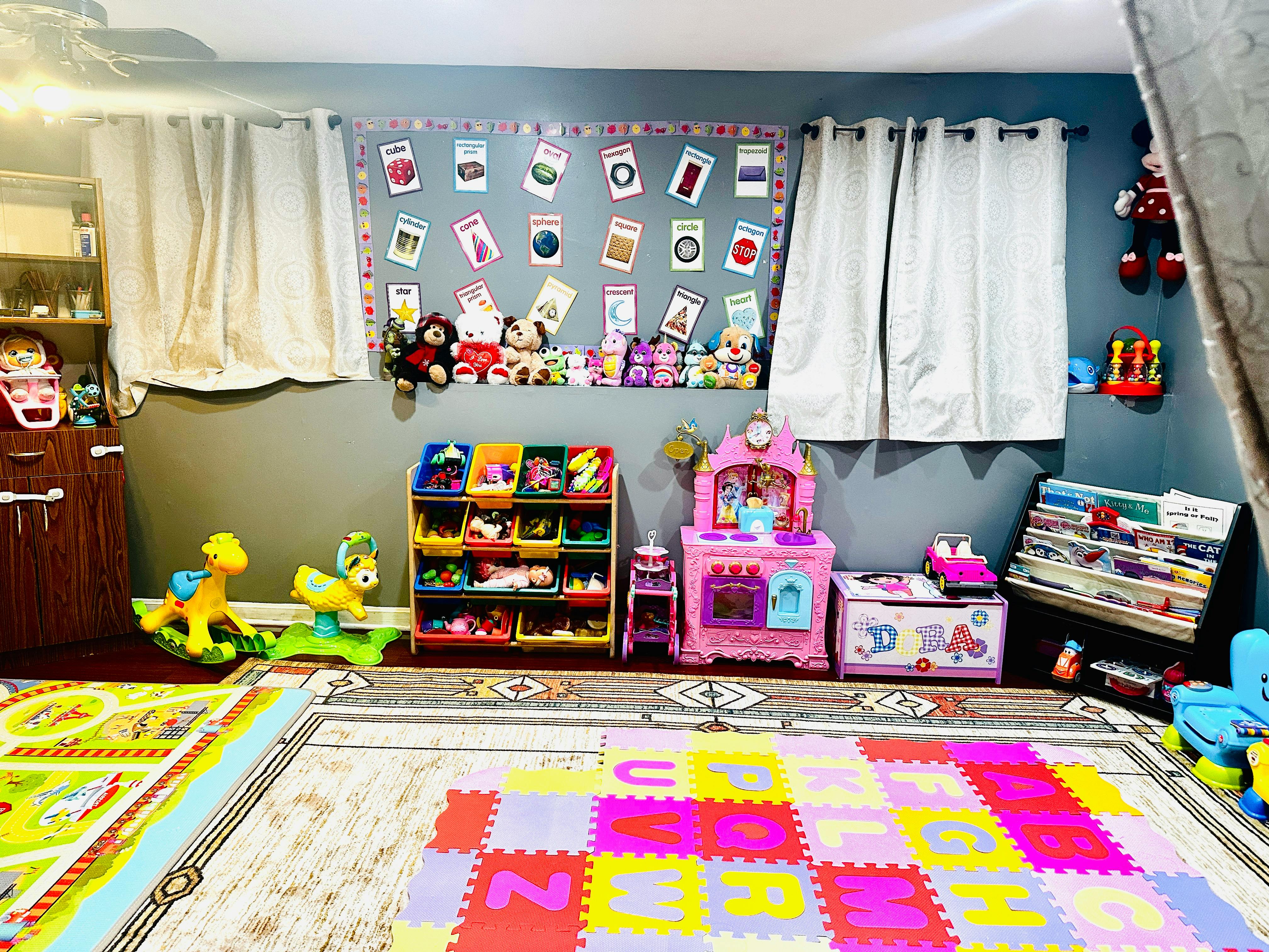 Playroom with toys, shelves, and alphabet floor mats