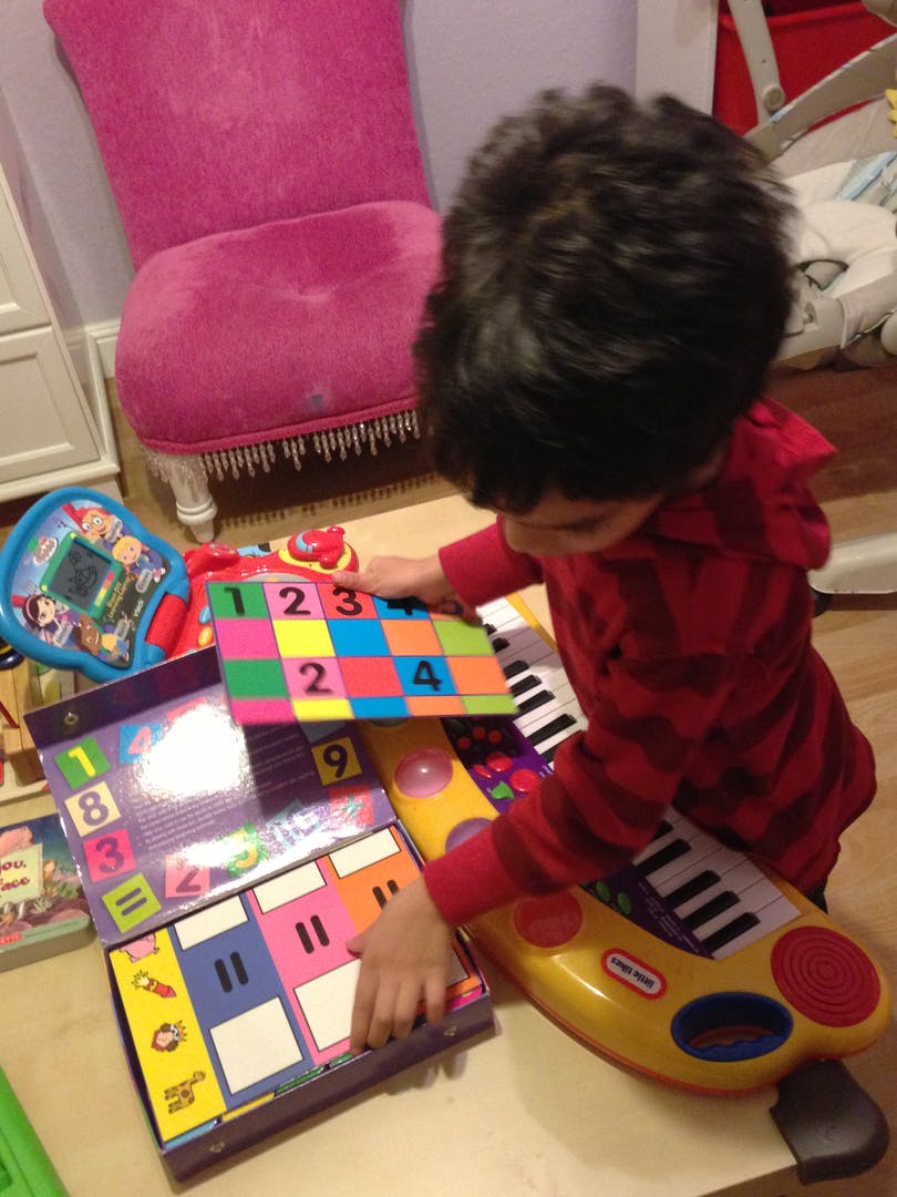 Child playing with colorful number blocks and a toy piano