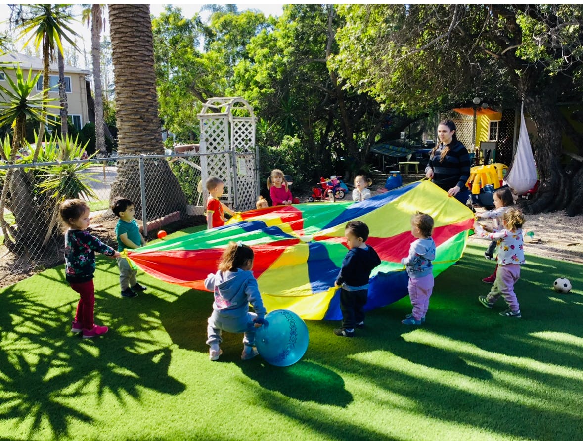 Children playing with a colorful parachute on a grassy area