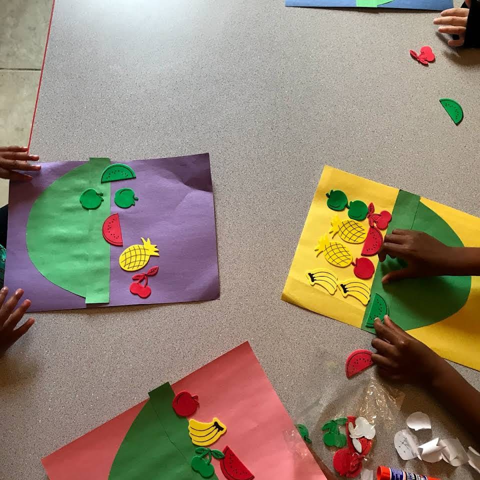 Children's hands working on fruit-themed craft projects