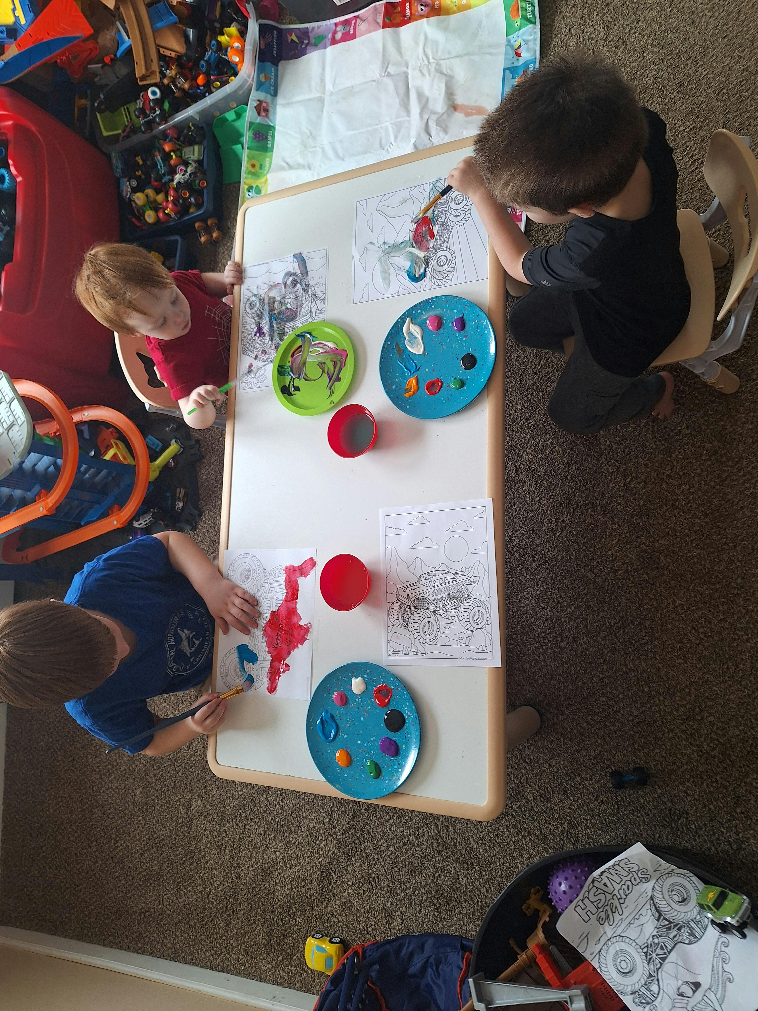 Three children painting at a small table