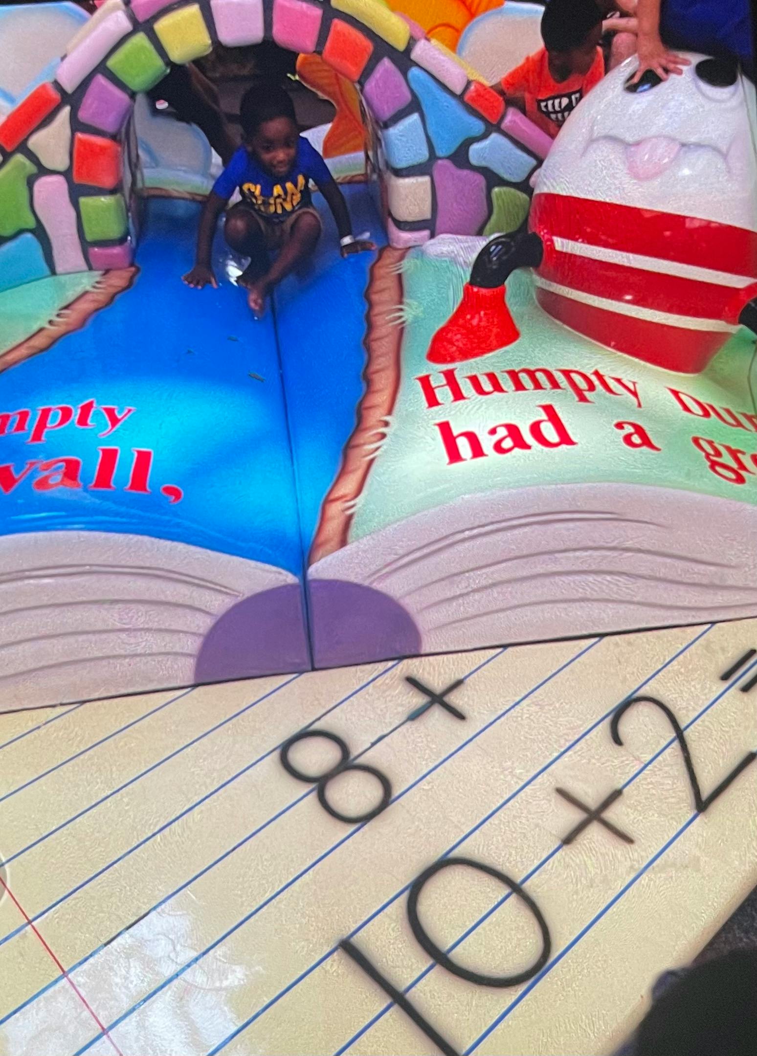 Child on a colorful inflatable slide shaped like an open book