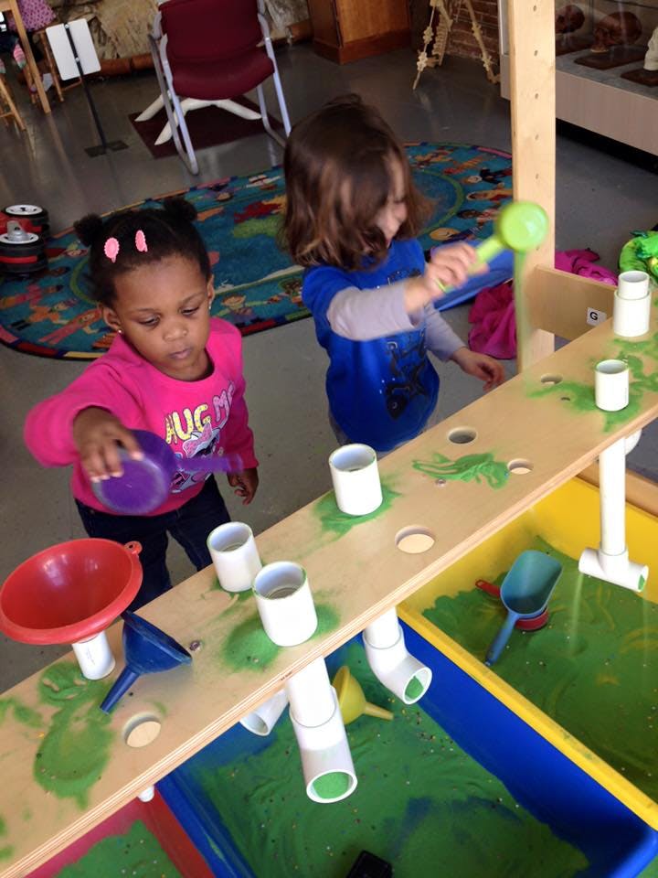 Two children playing with a sand and water table