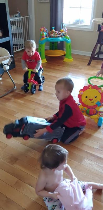 Three children playing with toys on a wooden floor