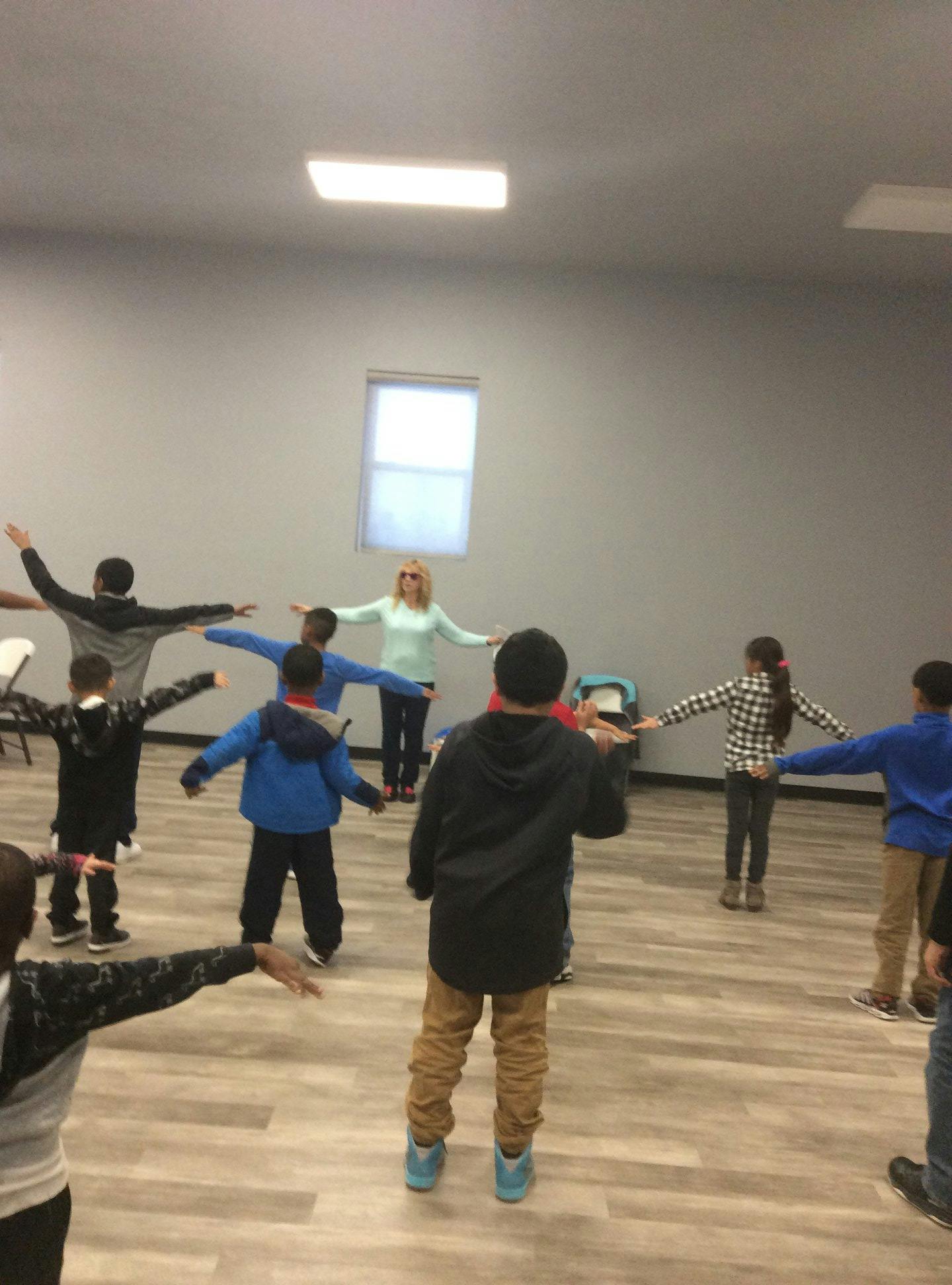 Adult and children standing in a circle with arms outstretched