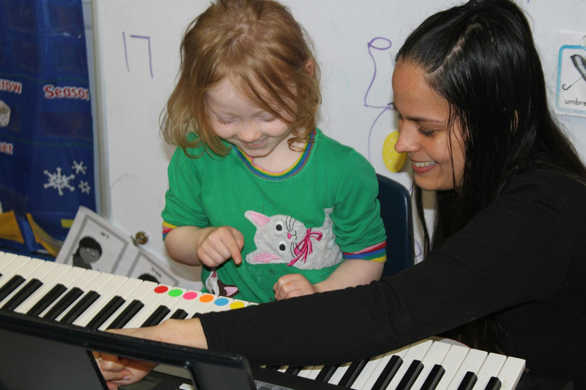 Adult and child playing an electronic keyboard with colorful stickers