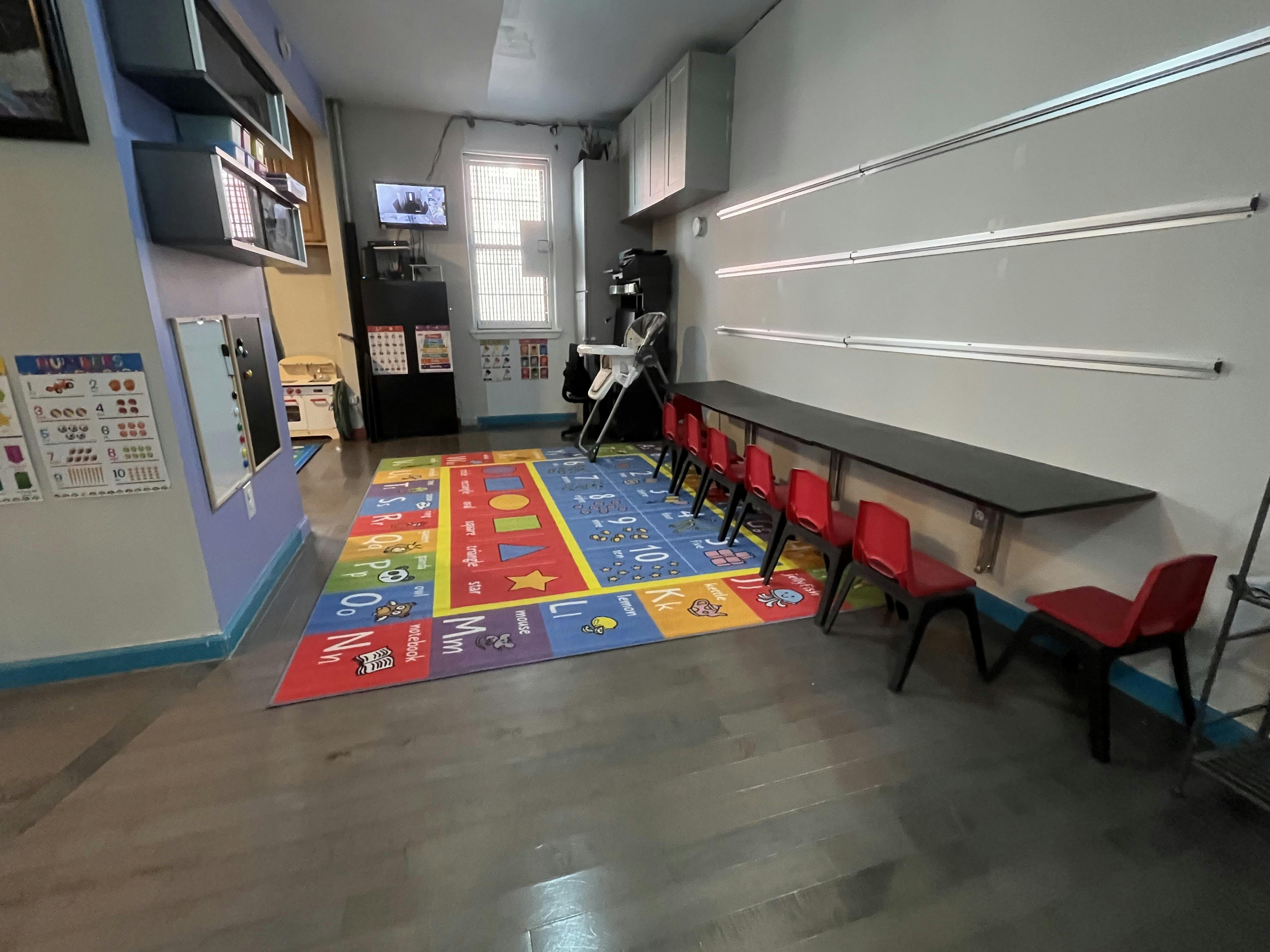 Playroom with colorful rug, small red chairs, and long table