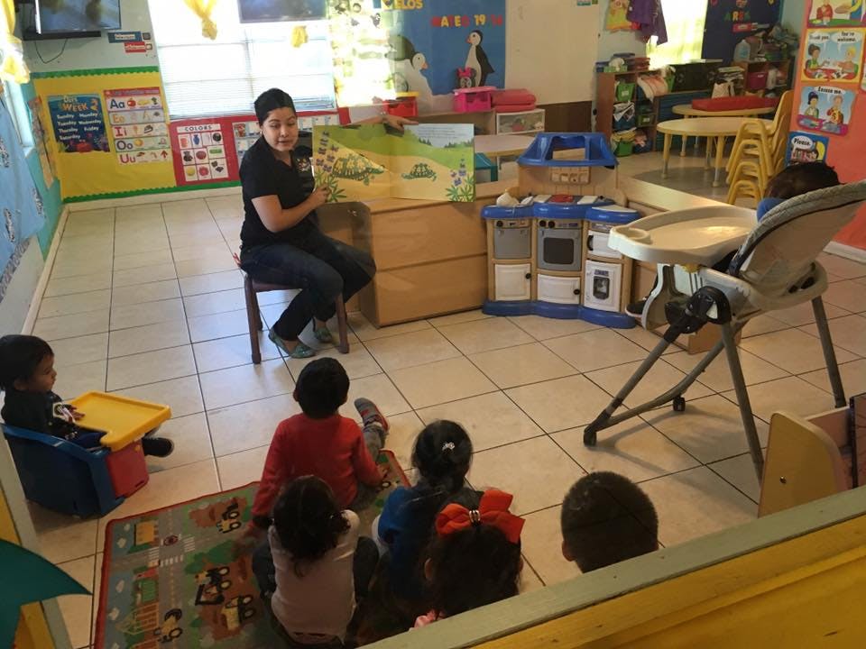 Person sitting on a chair reading to children in a classroom