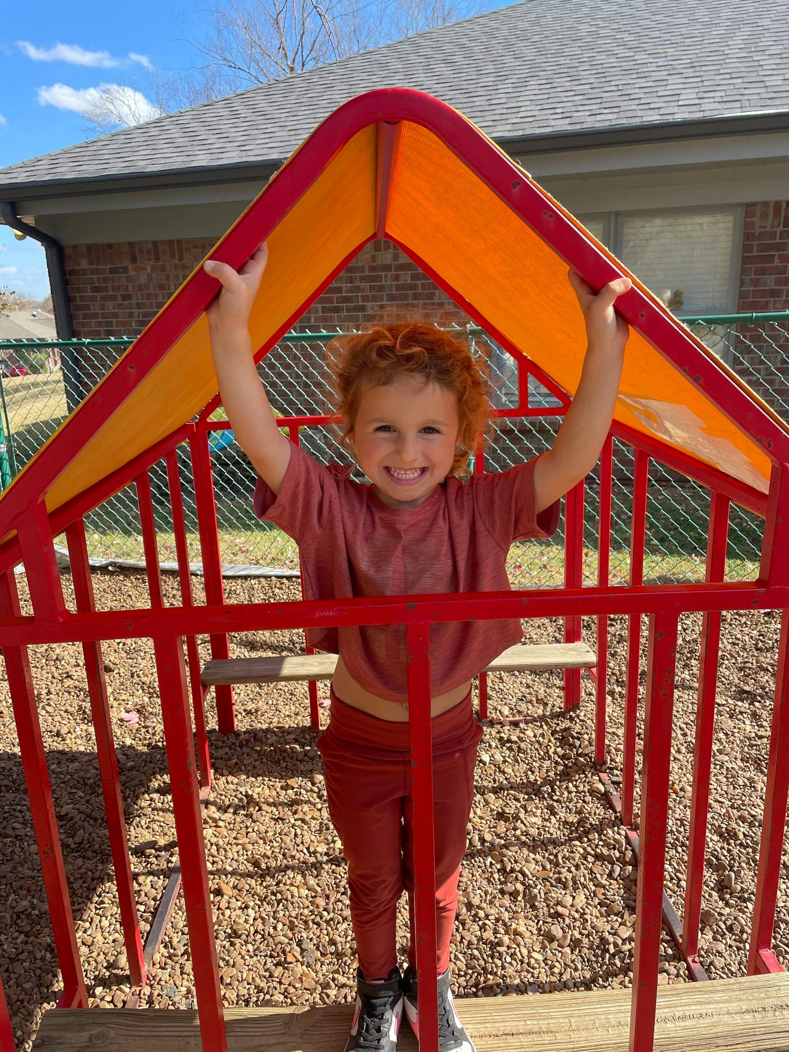 Child standing inside a red and orange play structure