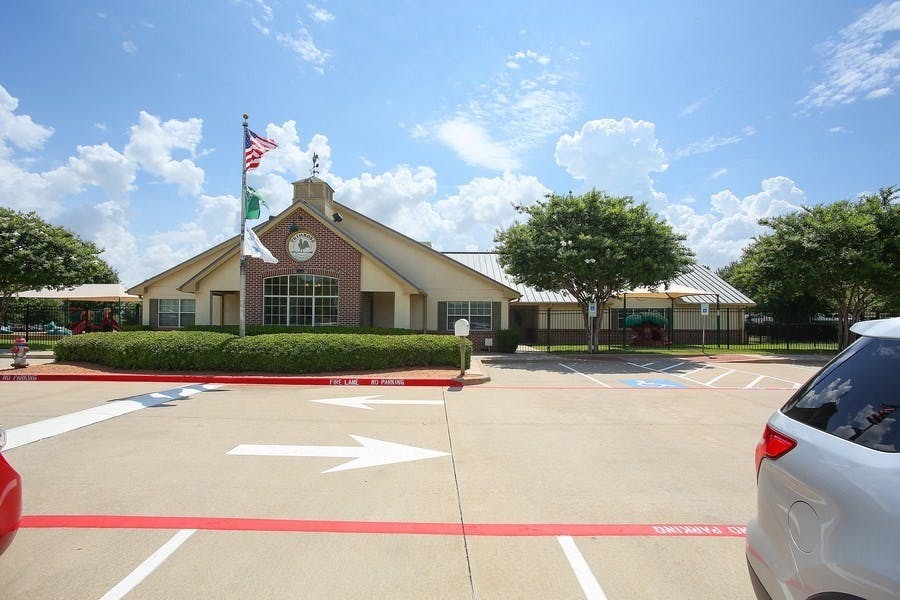 Building with a clock tower and flags in a parking lot