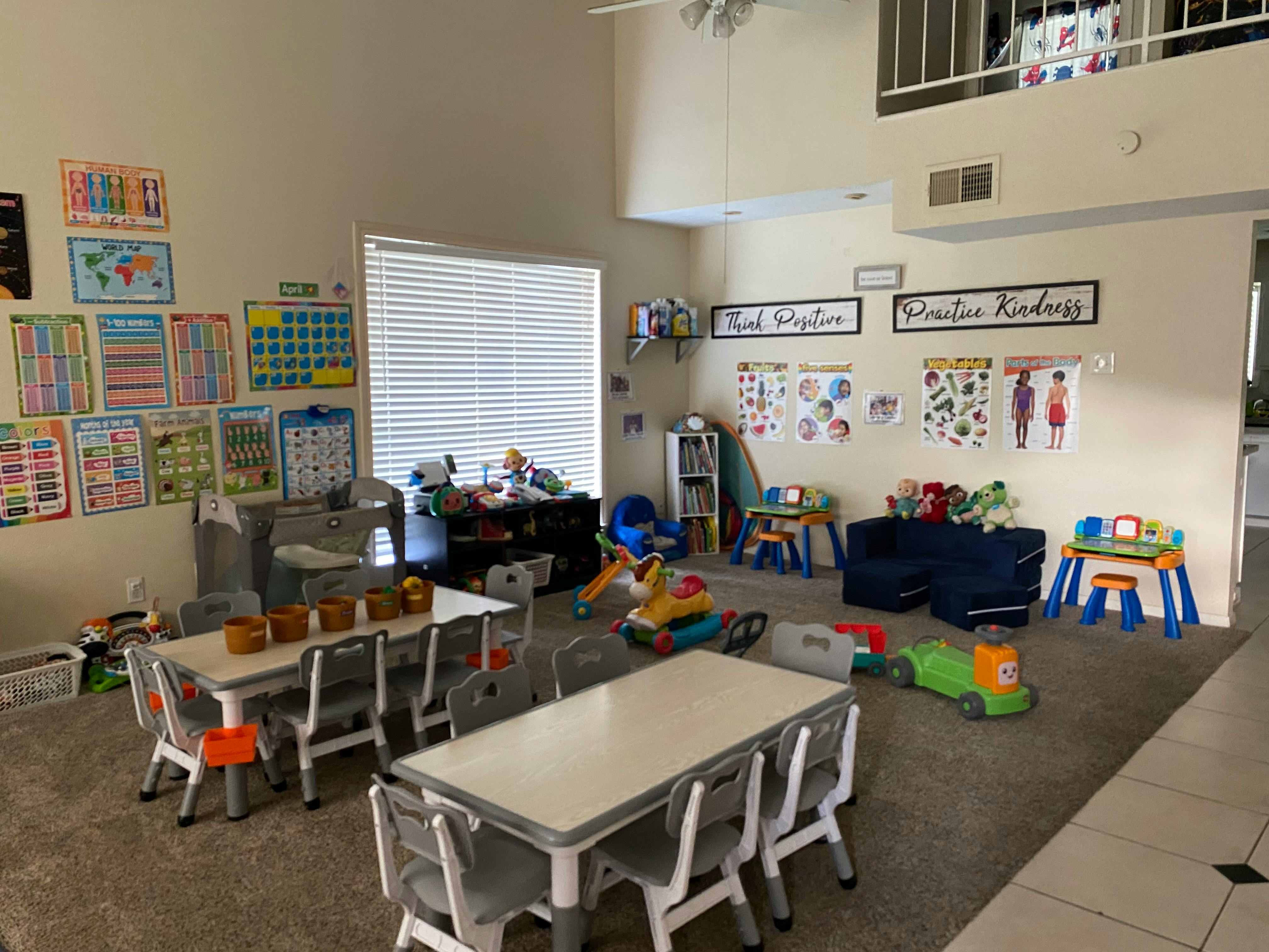 Classroom with small tables and chairs, educational posters, and toys