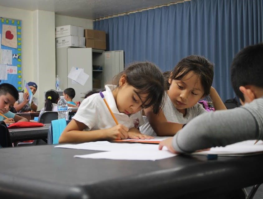 Children writing and looking at papers in a classroom