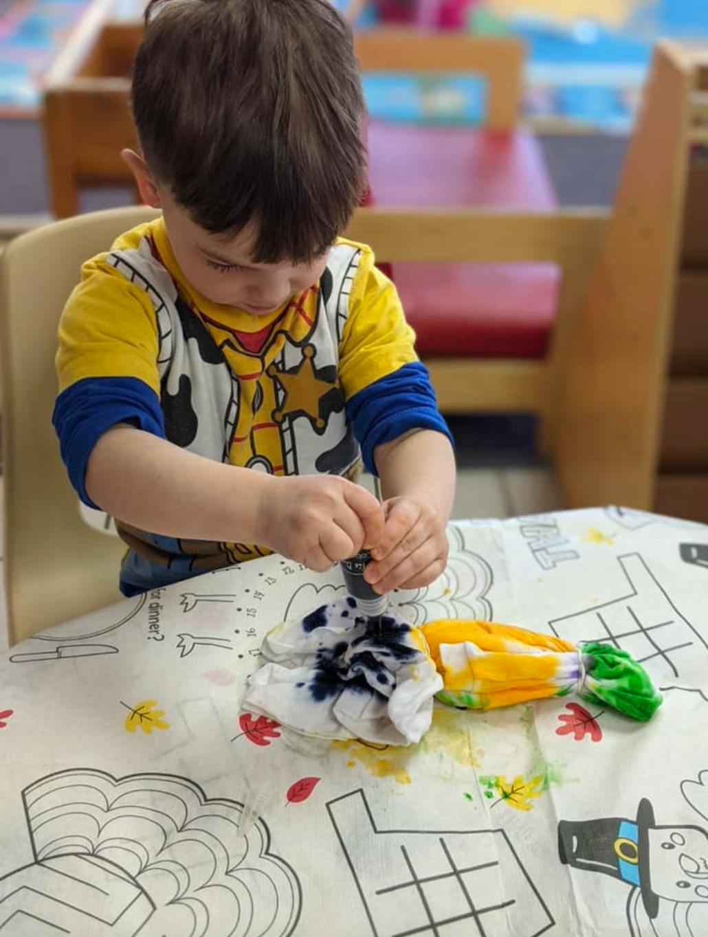 Child tie-dyeing fabric at a table