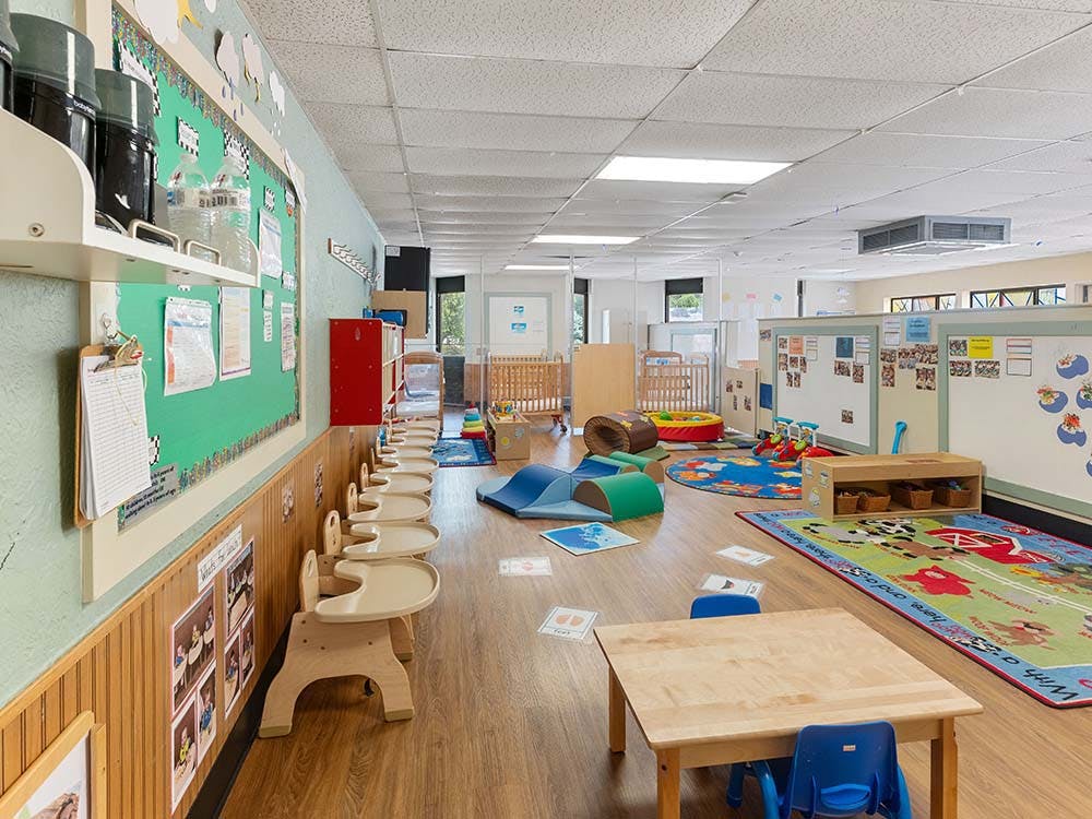 Empty colorful daycare classroom with small chairs and tables