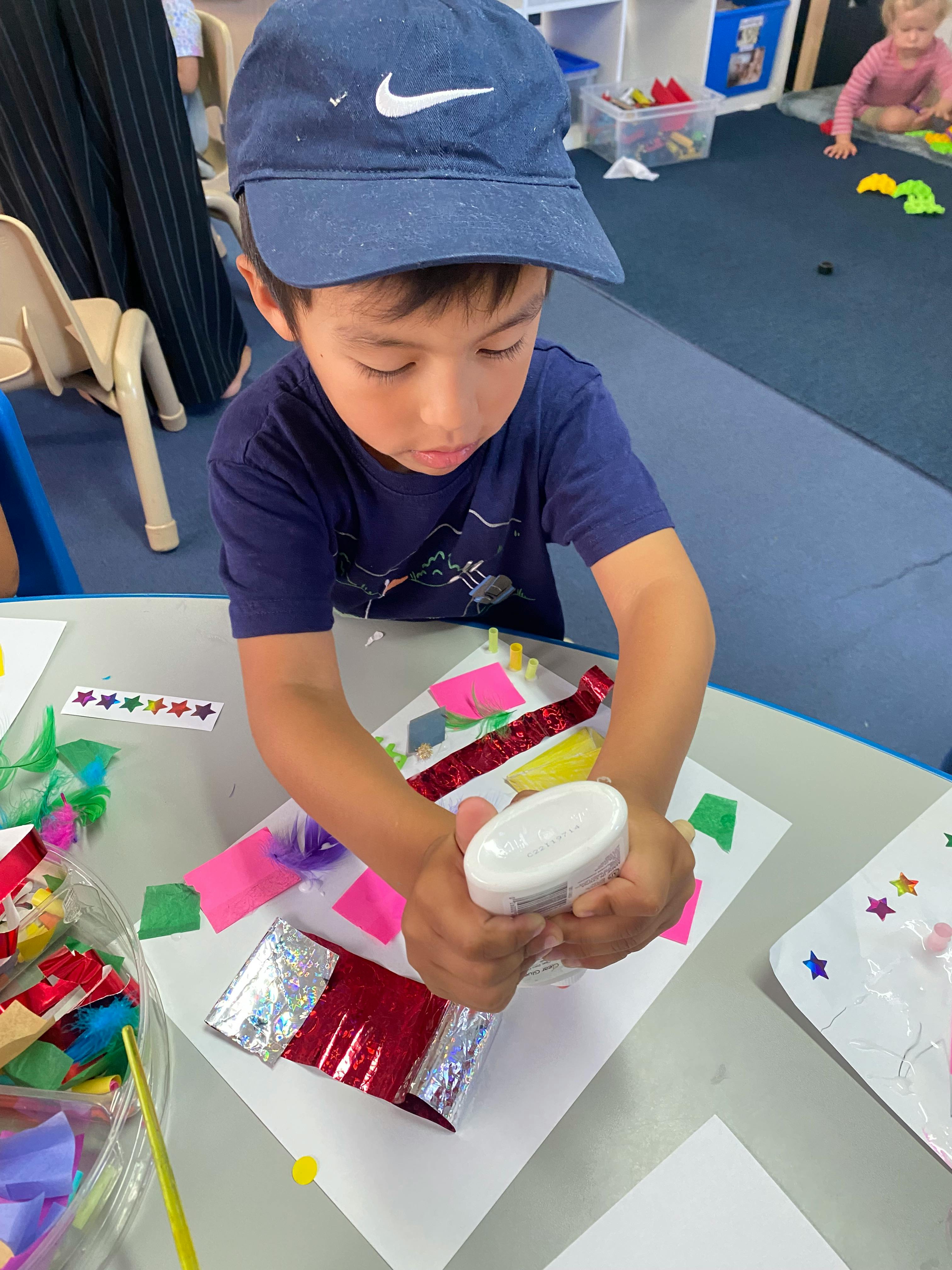 Child gluing craft materials onto paper