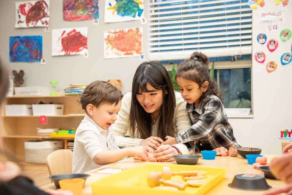 Adult and two children playing with modeling clay at a table