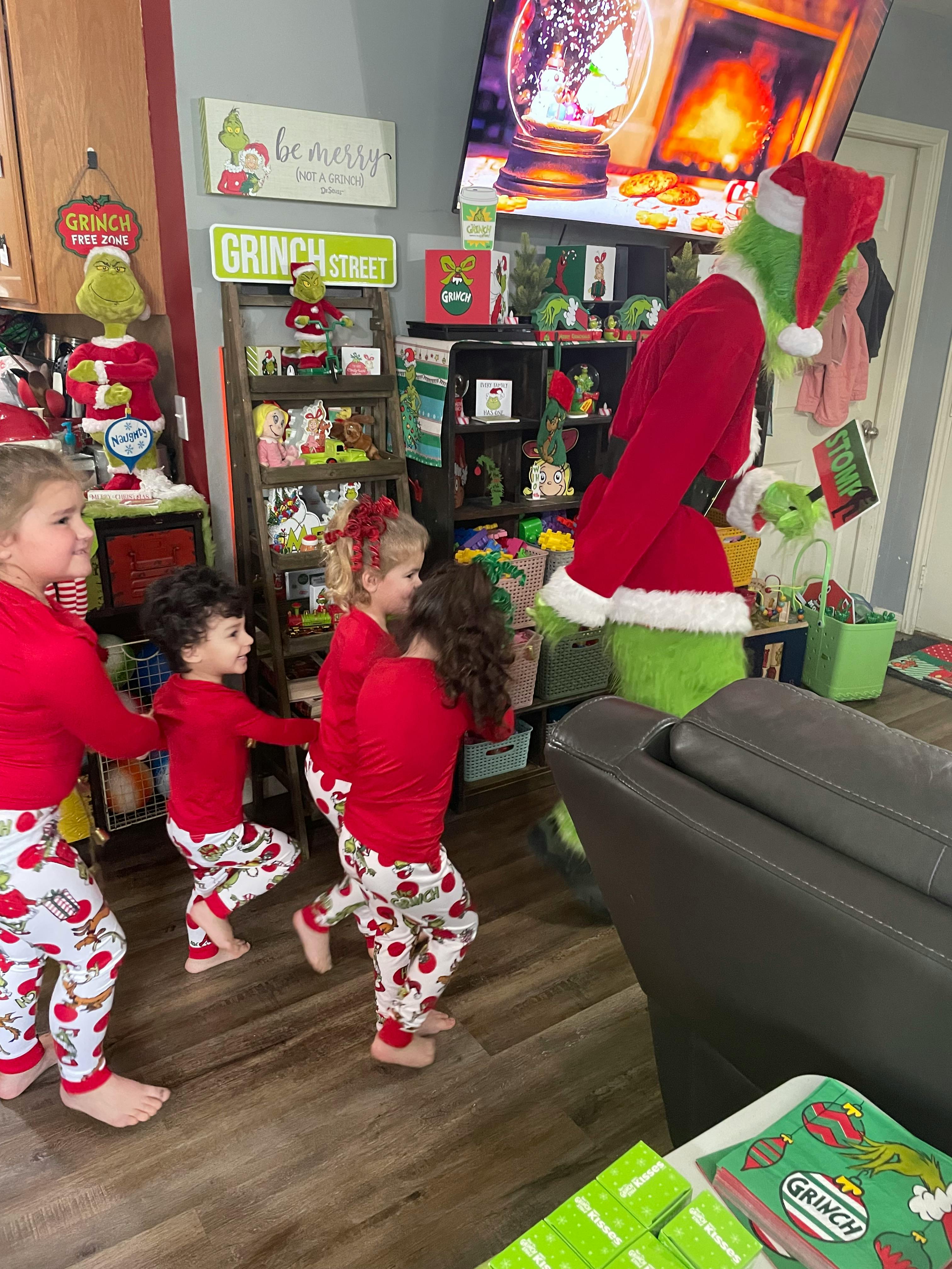 Children in pajamas interacting with a person in a Grinch costume