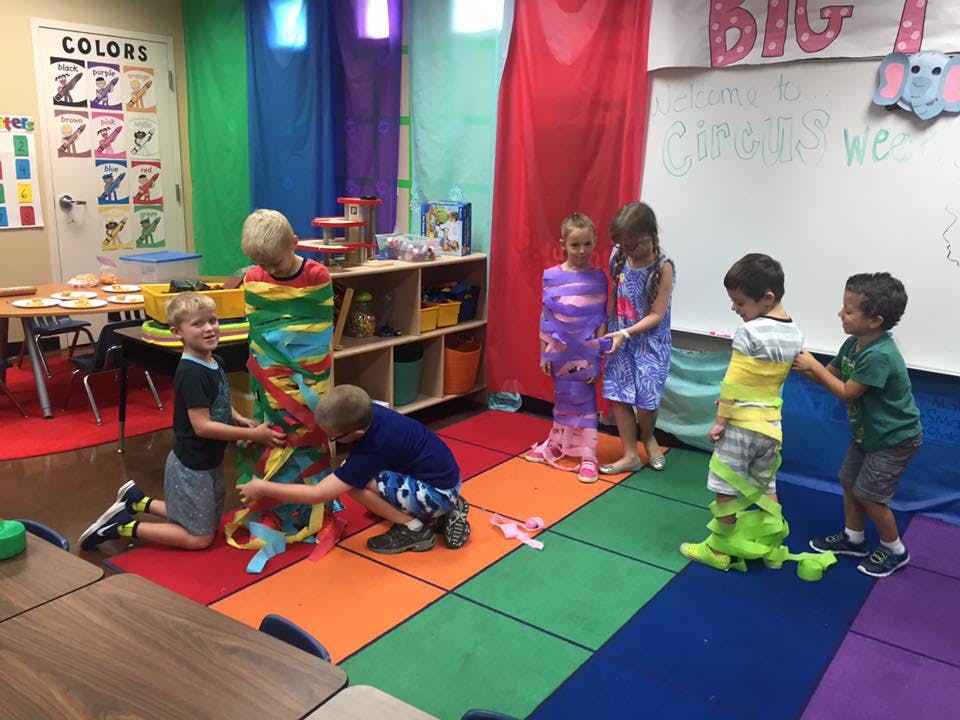 Children playing a game with colorful fabric in a classroom