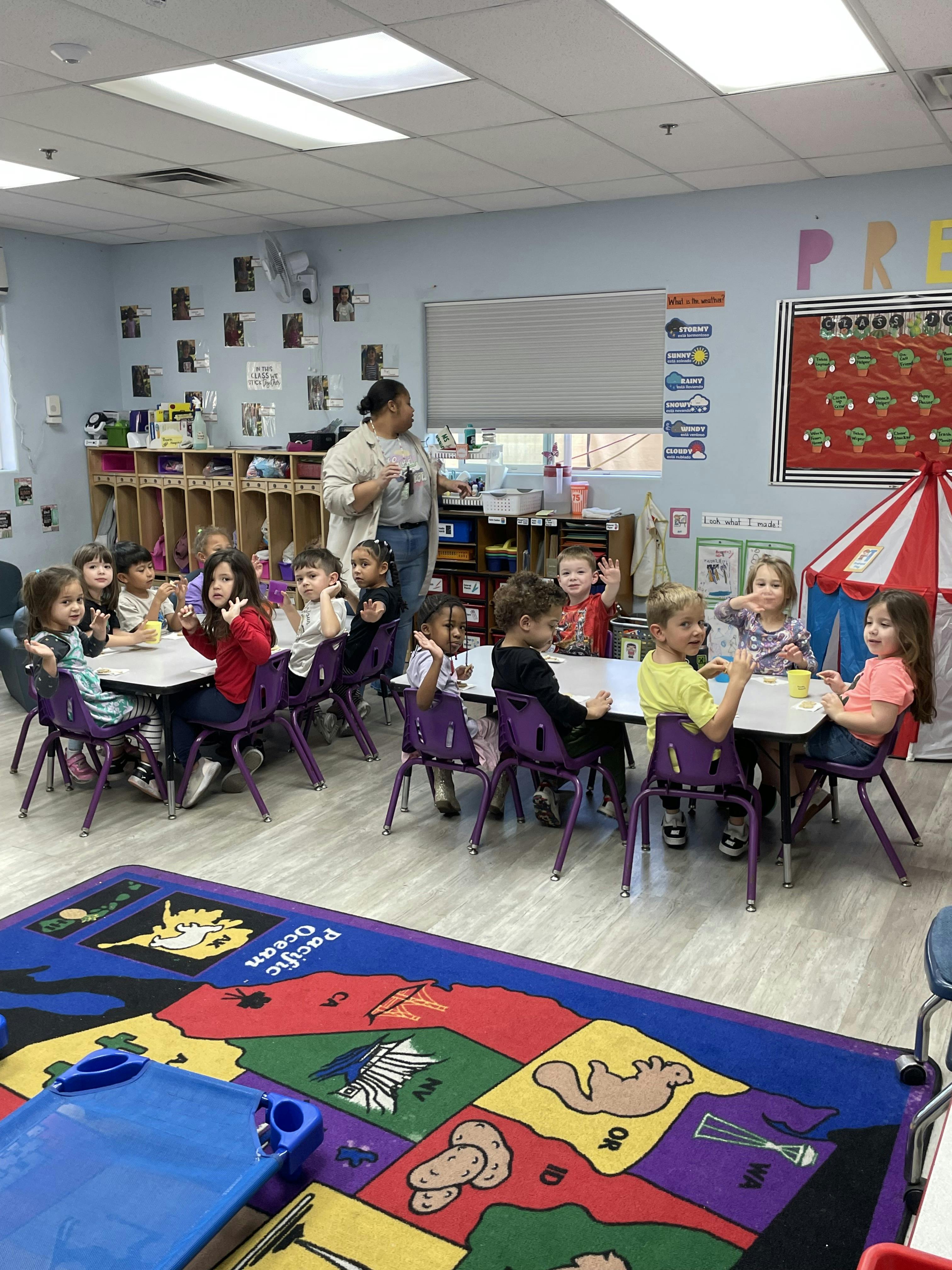 Teacher and group of children sitting at tables in a classroom