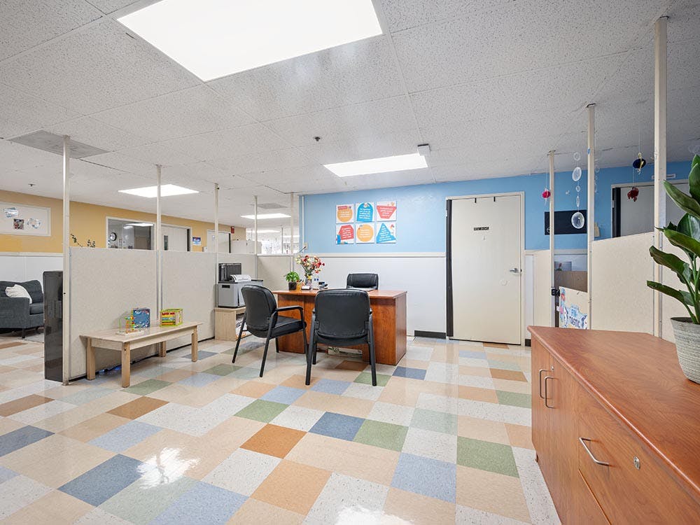 Reception area with a desk, chairs, colorful walls, and patterned floor