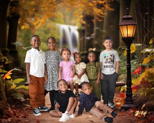 Group of children posing outdoors with a waterfall in the background