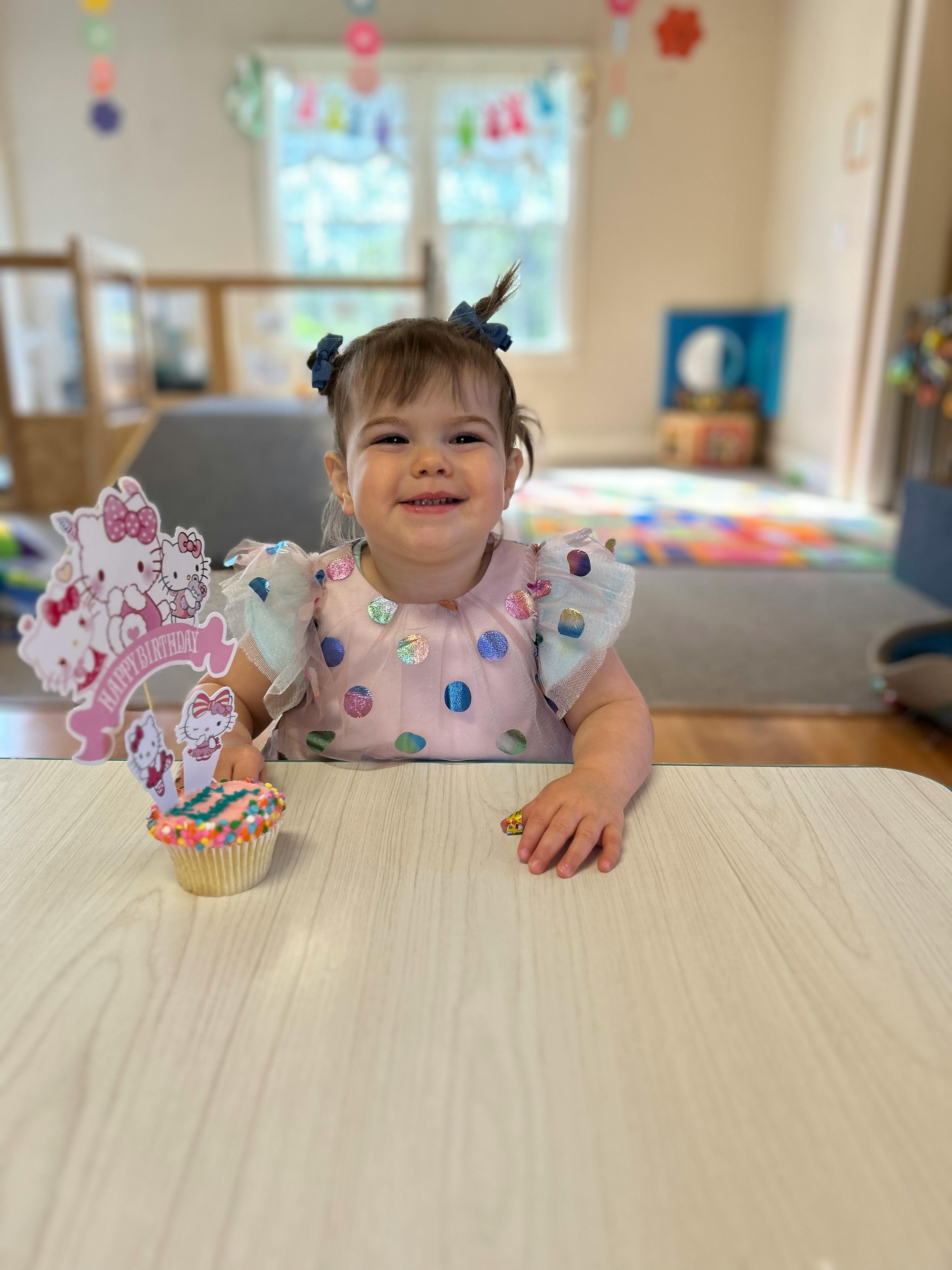 Child sitting at a table with a cupcake and a Hello Kitty decoration