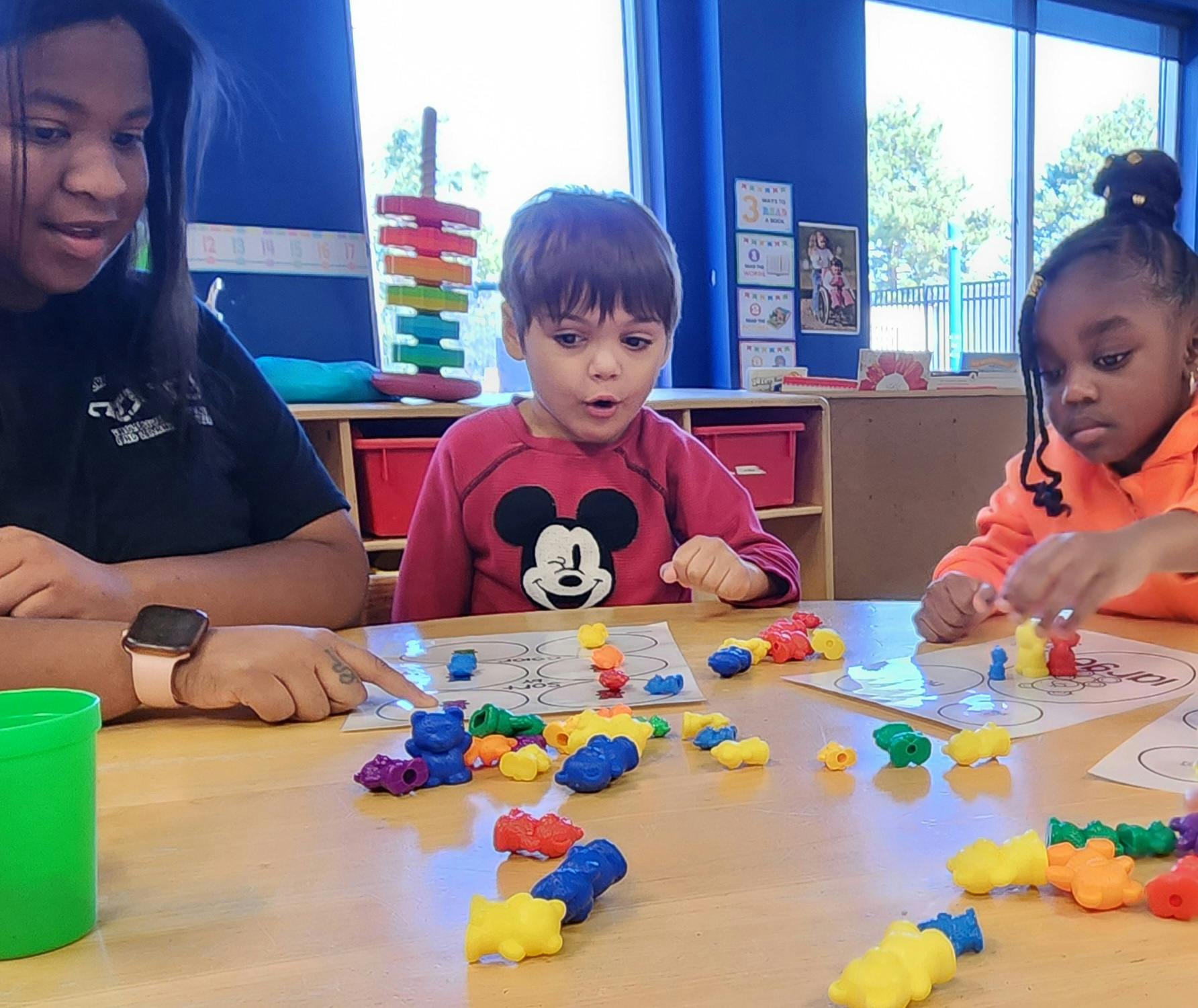 Three children playing with colorful connecting toys at a table