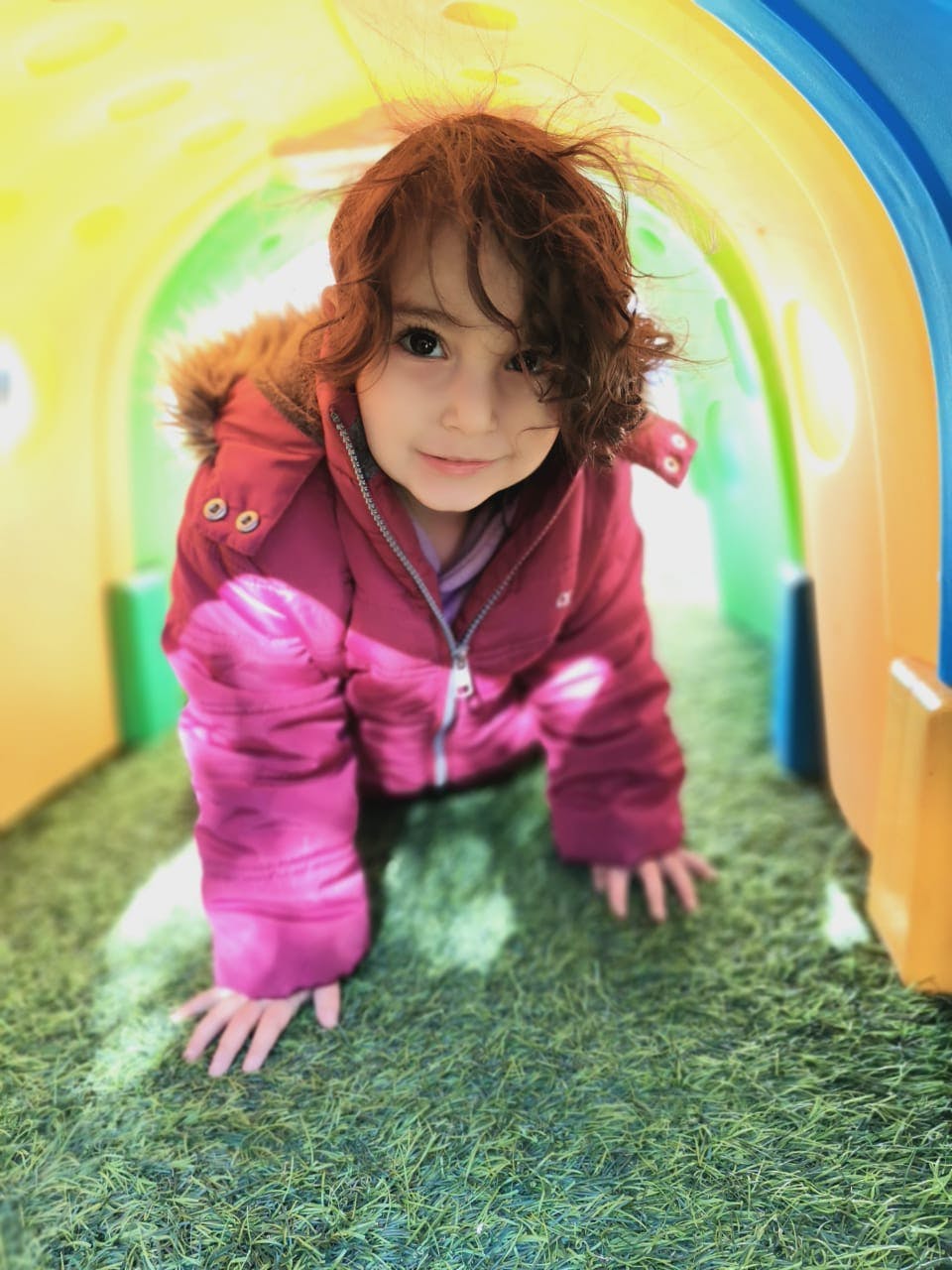 Child crawling through a colorful tunnel