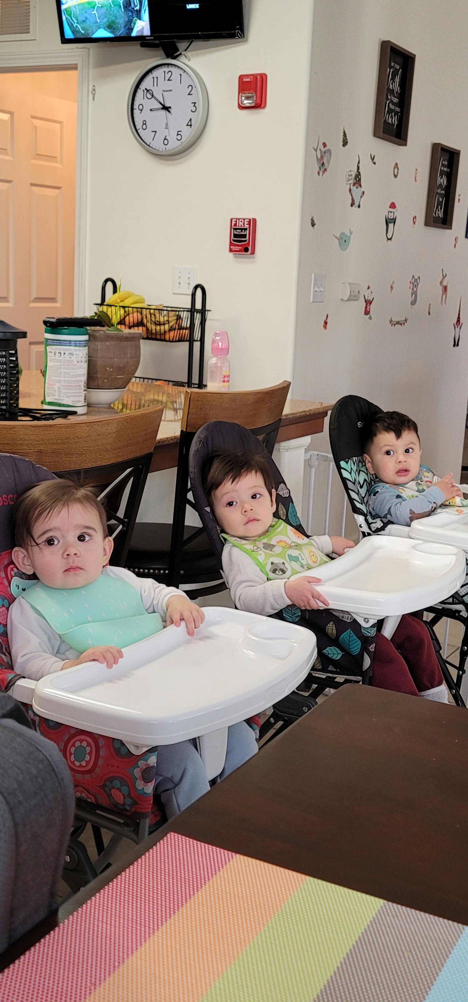 Three children sitting in high chairs