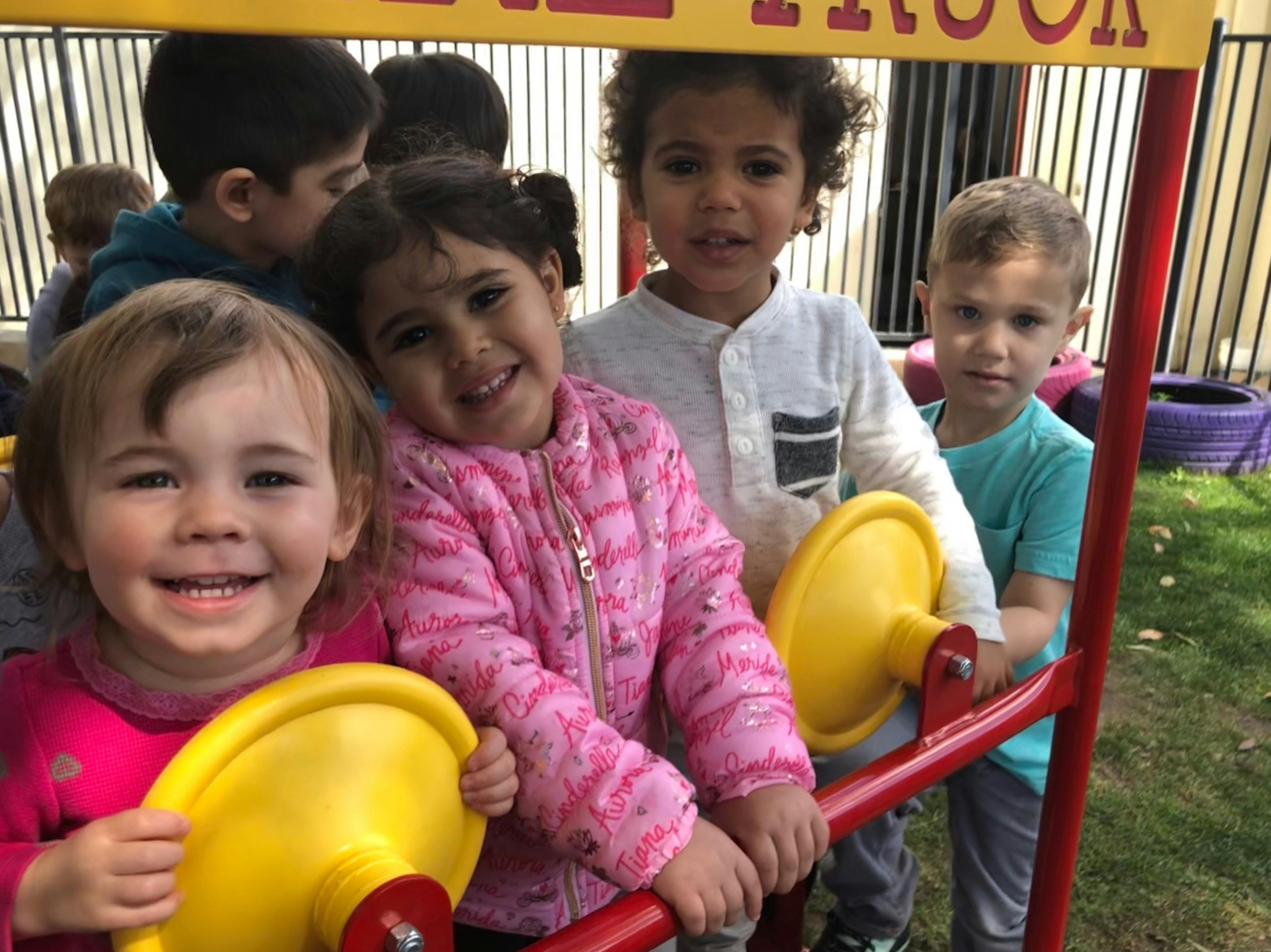 Group of children playing on a red and yellow play structure