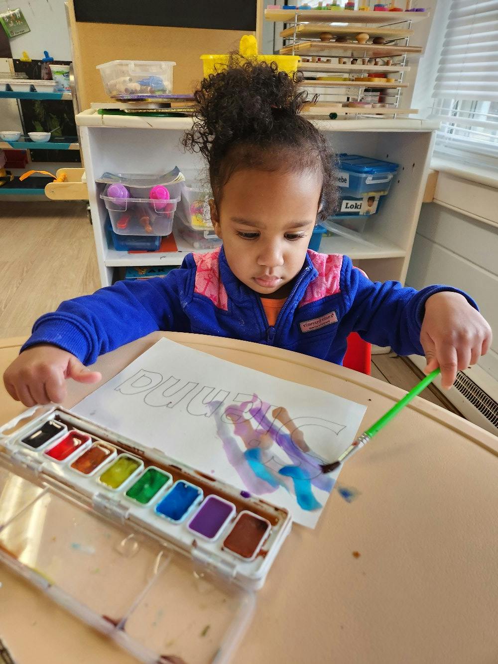 Child painting with watercolors at a table