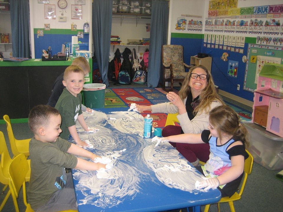 Adult and children playing with shaving cream on a table