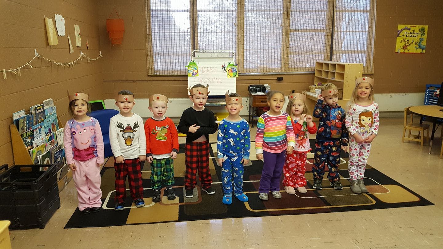 Group of children in pajamas standing in a classroom
