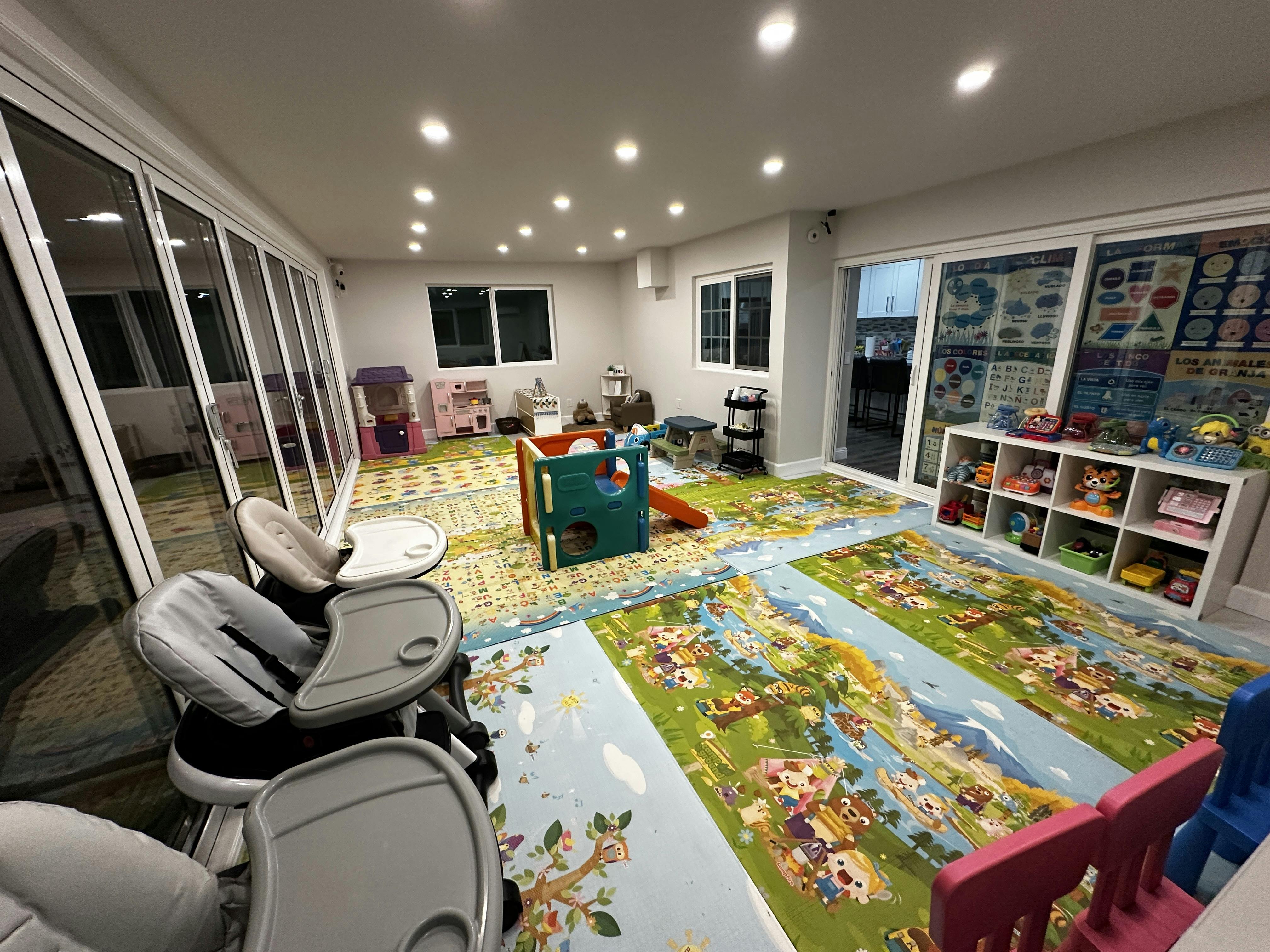 A children's play area with colorful floor mats, high chairs, and toy kitchens