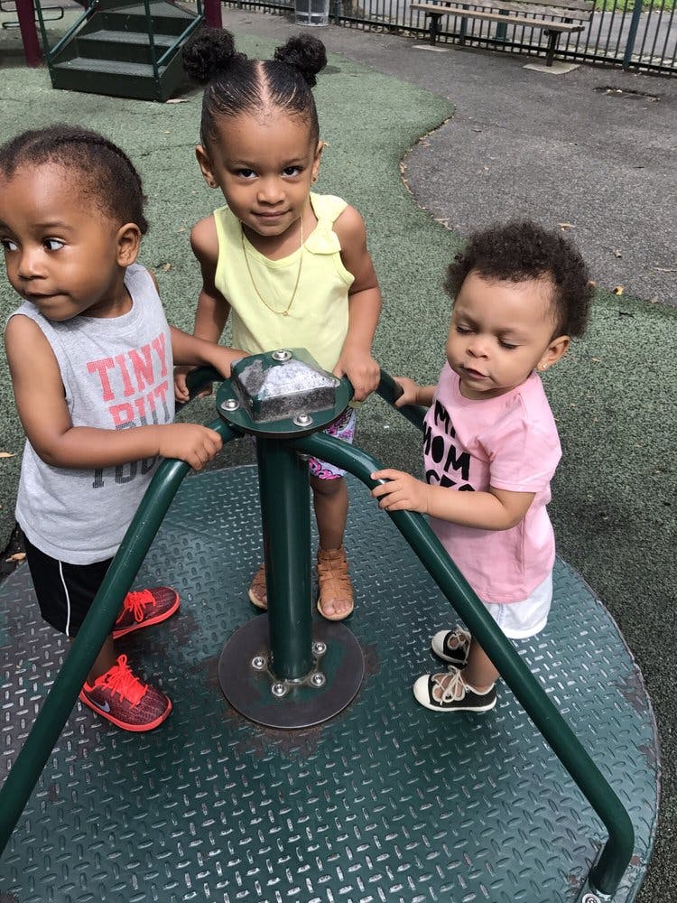 Three children on a playground merry-go-round